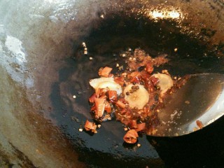 牛蛙香锅,用锅里的余油小火炒调料，依次放入姜片、花椒、干辣椒炒出香味