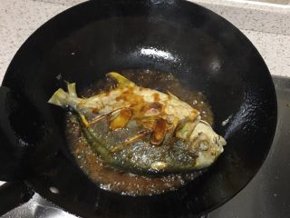 粤菜香煎鱼,将料汁均匀撒入已经煎熟的鱼中