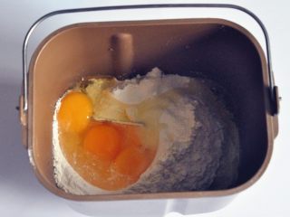 蔓越莓萨琪玛,将面粉、泡打粉和鸡蛋倒入面包机桶中