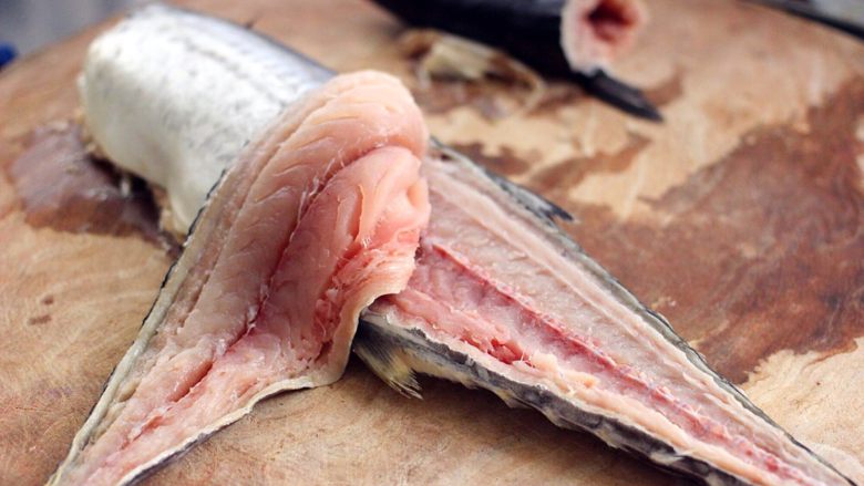 翡翠鲅鱼酸汤馄饨,然后从鲅鱼的尾部开始用刀往上片鱼、如图