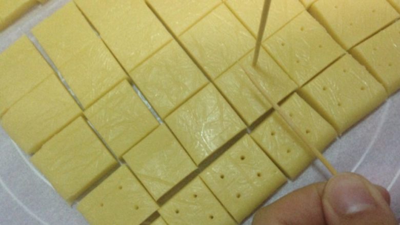 奶油奶酪小方,放入冰箱半小时后取出切小块，用牙签在方块上戳洞方便烤熟