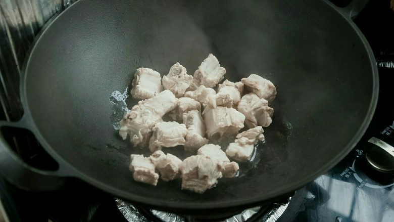豆棒烧排骨,锅中油热后放入排骨翻炒。