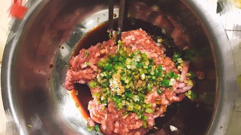 豇豆猪肉馅水饺,凉水和食用油全部倒入。用筷子顺一个方向快速搅拌，直至肉馅呈棉絮状