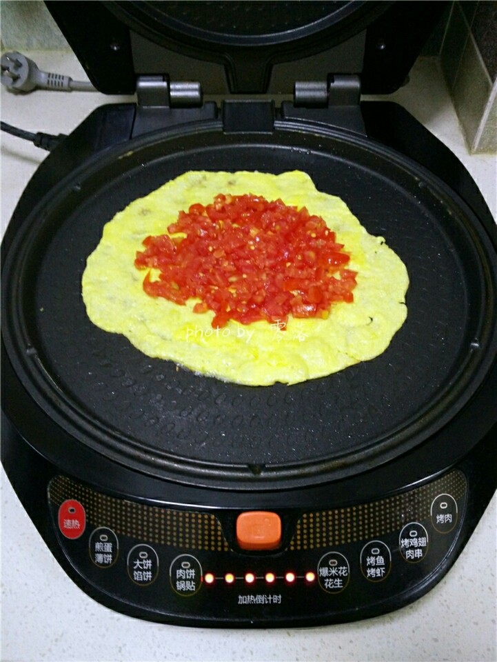 西红柿鸡蛋披萨,蛋液稍稍凝固后，在蛋饼中间铺上番茄丁；