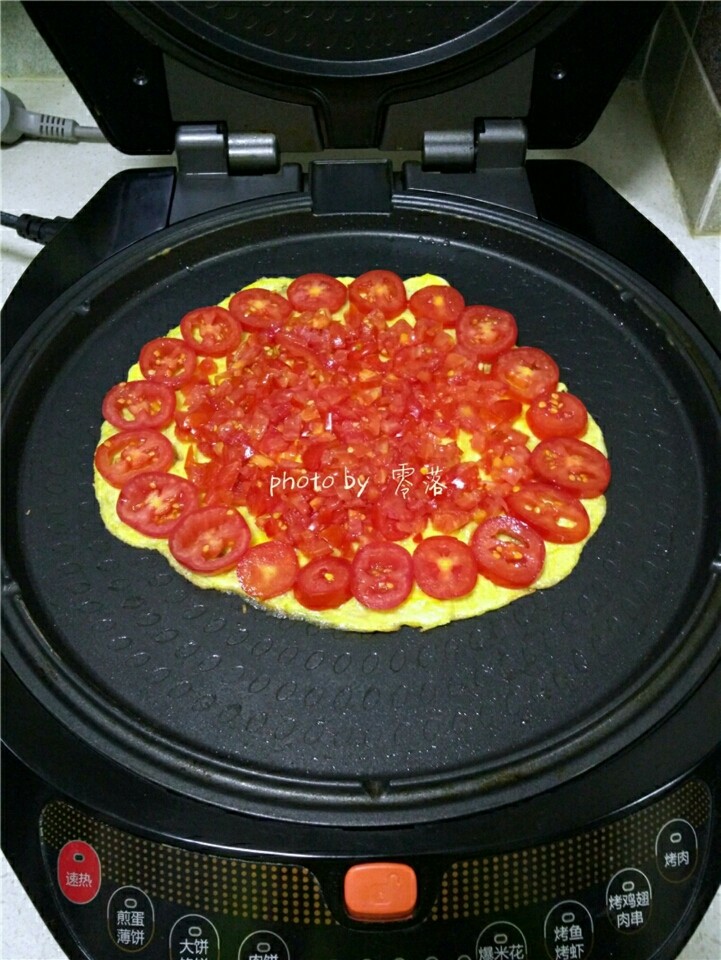 西红柿鸡蛋披萨,预热程序结束后，关闭电源；在蛋饼四周铺上番茄块；