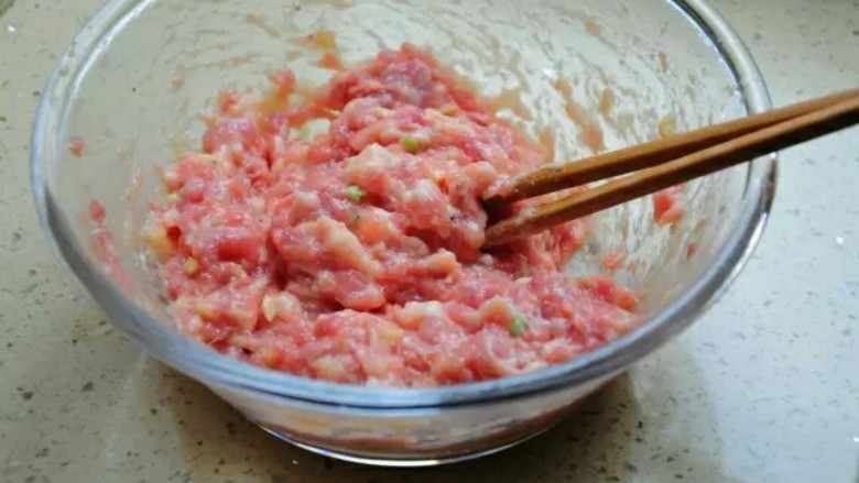 清蒸狮子头,拿一双筷子将调好的肉馅朝一个方向搅拌均匀，直到肉变得很有韧劲。