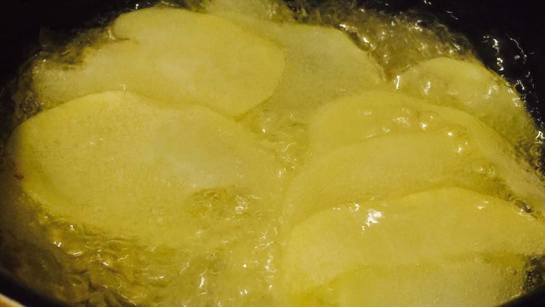 家庭健康薯片,锅中热油，油温5成热后放入土豆片。（五成热是木头筷子放入油中有细细的小泡。）全程小火炸制