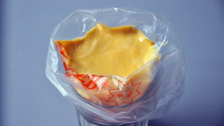 蛋黄饼干,将一次性裱花袋套在一个杯子上，倒入面糊。