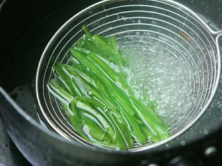 夏日小菜凉拌土豆丝,青椒丝放在沥勺内，放在开水里过一下水立刻捞起。