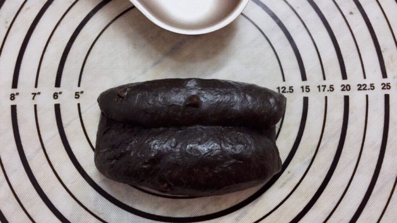 黑可可热狗包,取小份面团，擀成椭圆形，两边中间卷起来，收口捏紧，搓成橄榄型