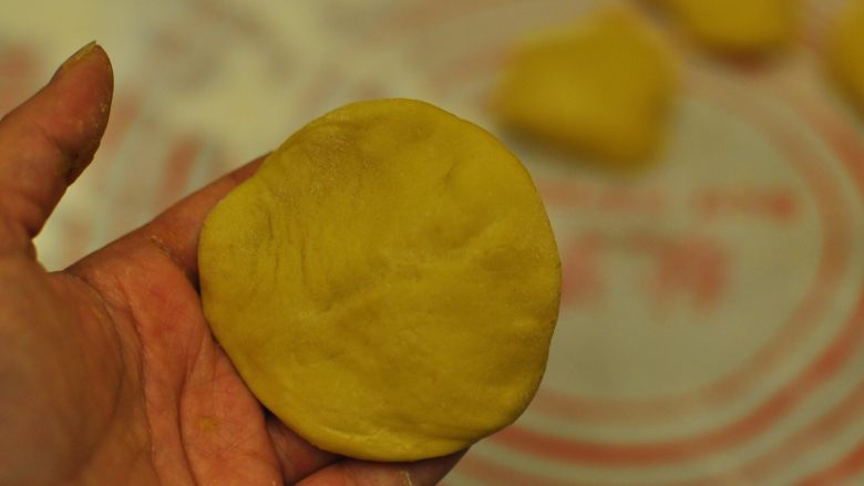 南瓜豆沙包,用手把小剂子摁一下，变成扁平状