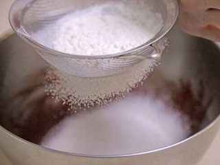 红丝绒曲奇,低粉和泡打粉混合物过筛后，加入上一步的混合物中，拌匀。