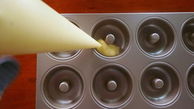 椰香甜甜圈（烤箱版）,甜甜圈面糊装进模具里，如果模具不是不粘模具就在模具壁上轻轻扫一层融化好的黄油。