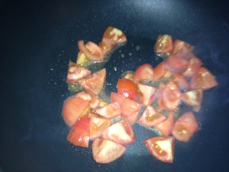 番茄炒年糕,如图把已經切成塊狀的番茄放入鍋裡，翻炒幾下然後小火。