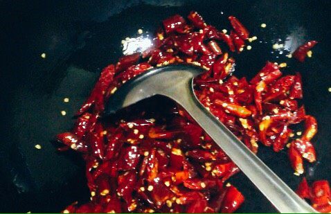 刀口辣椒,炒锅润油后下入干红辣椒段小火煸炒。
