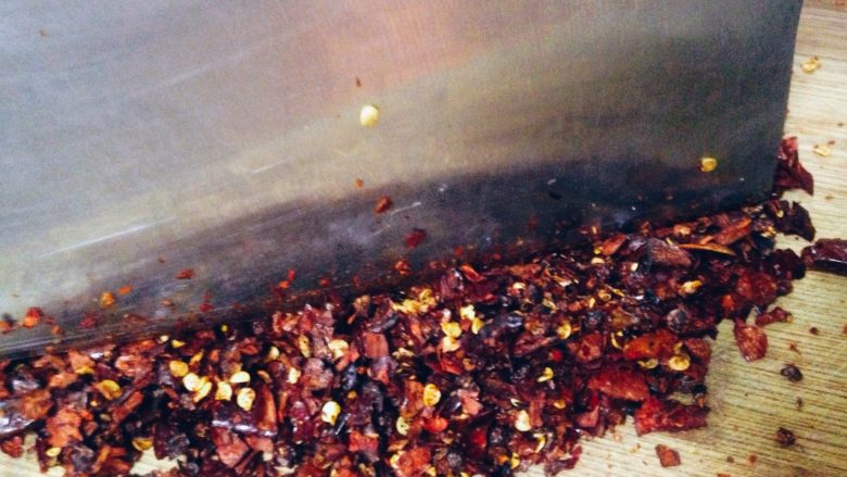 刀口辣椒,将晾凉的辣椒和花椒置于砧板上用刀剁碎。