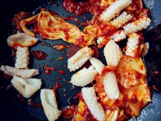 韩式酸辣鱿鱼盖饭,下辣白菜、鱿鱼和盐，翻炒几下，出锅前洒少许鸡粉提味