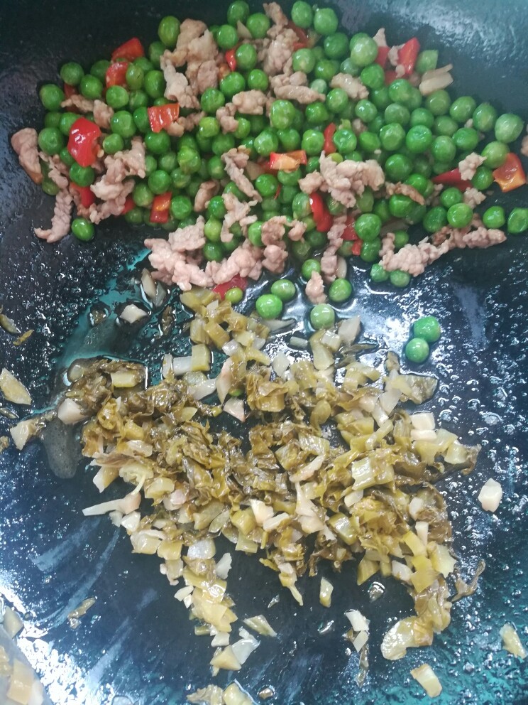 酸菜肉沫炒豌豆,把炒过的食材扒在一边，倒入挤干的酸菜单独炒半分钟。（为防止肉沫炒老）