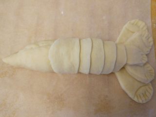 龙虾面包,制作身体的壳：再取一块面团，揉成长条，切成剂子，擀薄成圆片后对半切开，一片压一片，按照小龙虾外壳的样子包好。中间用少许蛋液粘合