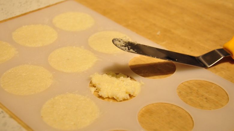 好吃到停不下嘴的椰子脆片,将瓦片模具放在油布（油纸）上，用“L”抹刀取适量的面糊填充到模具中，用抹刀抹平。