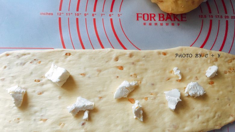颗颗香浓花生粒入口的南瓜乳酪软欧包,依次将面团擀成长舌状，中间撒上散乱的奶油奶酪，由上往下卷起来。