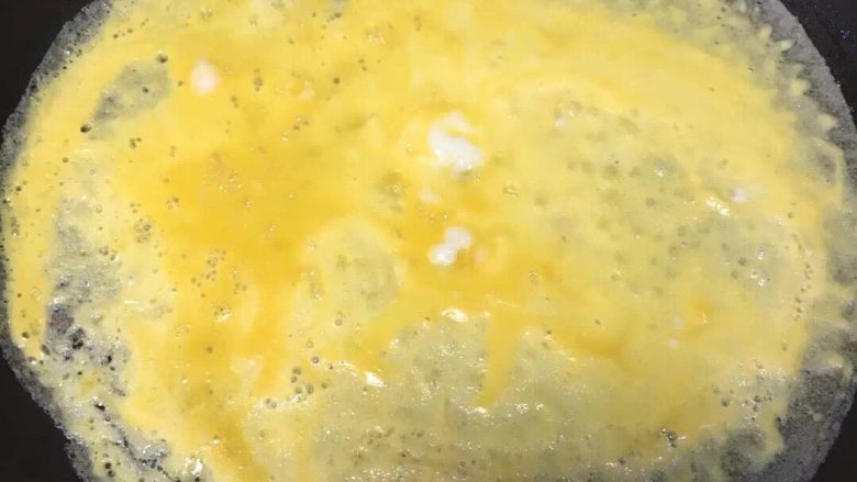 蛋包饭,轻轻倒入打散的鸡蛋液，尽量均匀平铺锅底，待蛋皮成型