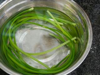 手撕蒜苔,取一大容器，放适量冷水，将焯水的蒜苔捞起放入。