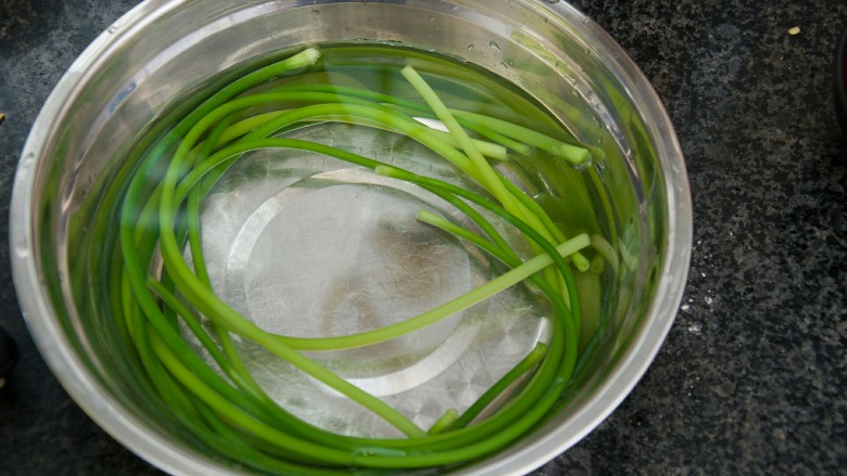 手撕蒜苔,取一大容器，放适量冷水，将焯水的蒜苔捞起放入。