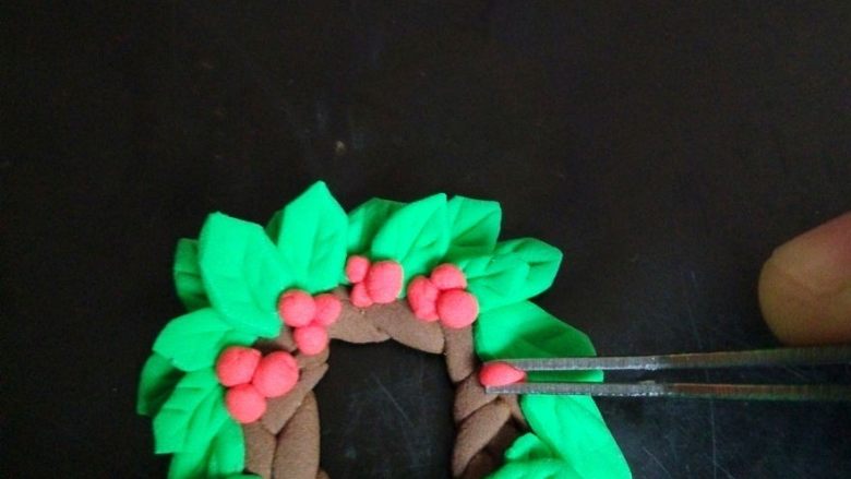 卡通树桩屋翻糖蛋糕,榭寄生的花环：用剪刀剪出叶子，花边是搓条编辫子，然后搓红色小球粘上。