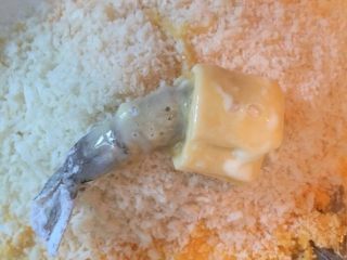 芝士虾球,蘸满蛋液的虾仁，最后包裹上面包糠，这里包裹的同时可以简单地用手把虾身部分紧实捏圆。
