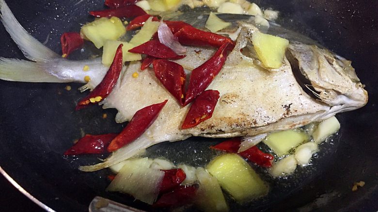 蒜苔烧金鲳鱼,不粘锅里倒入适量的食用油，烧六七成热，腌好的鲳鱼用厨房纸吸干水份，放入油锅俩面煎一下，然后放入姜蒜、干辣椒；