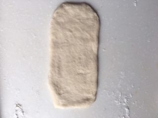培根芝士卷,取一个面团，稍按扁后擀成比培根略短且略宽的长方形