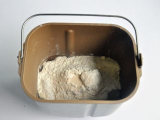 蔓越莓吐司布丁,把液体材料放入面包桶中，面粉铺在上面，对角分别上放上盐、糖A、奶粉，在面粉中间挖一个小坑，放上酵母，启动面包机揉面程序10分钟。