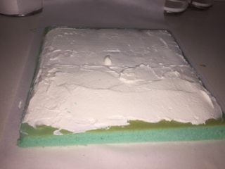 蓝天白云蛋糕卷,再把蛋糕翻过来，就是蛋糕的正面朝上，把奶油铺在上面，靠近身体的部分可铺的厚一些。