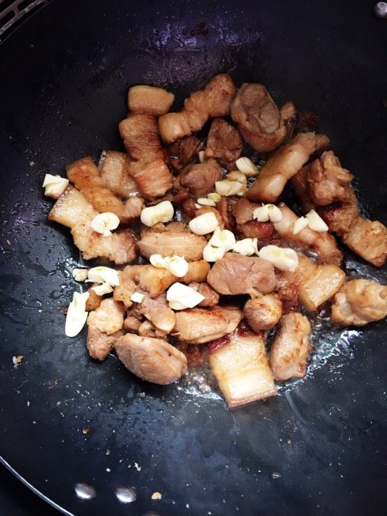 梅菜煨春笋,将肉煸香变色出油，放入切碎的蒜瓣炒香。