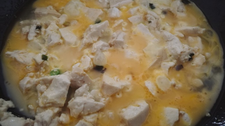 鸡蛋刨豆腐,炒到豆腐稍微有些出水时，将蛋液均匀的倒在豆腐上。