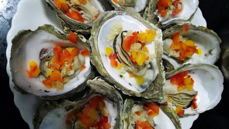 水蒸海蛎子+#人民的美食#,先将蒜蓉，彩椒点缀在每个海蛎子上，量随意