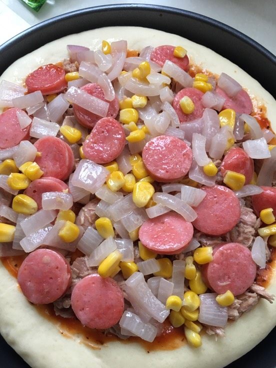 什锦披萨,把金枪鱼肉和炒过的蔬菜铺在饼皮上