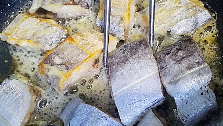 红烧带鱼+#人民的美食#,放入腌制好的带鱼，小火煎，用筷子翻面，轻点哦