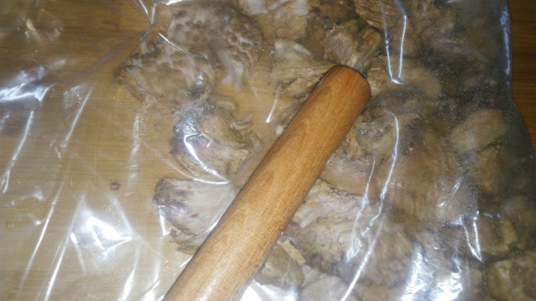 炒锅版猪肉松,将肉装进保鲜袋，用擀面杖一边擀一边敲，将肉敲散。
