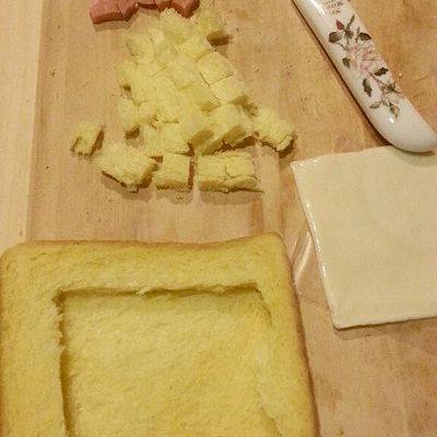 法式早餐 : 干酪太阳蛋吐司,把一片<a style='color:red;display:inline-block;' href='/shicai/ 13322'>面包片</a>放在底层，另一片切掉中间部分，切出的面包部分切成丁，火腿也切成丁。
