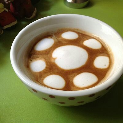 拿铁,4.用蒸汽管大发奶泡，将加热过的牛奶倒入咖啡内，中间加入，形成一个圆，边缘的小圆用勺子加入
