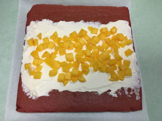 红丝绒蛋糕卷,蛋糕凉了以后在蛋糕表面涂上打发好的奶油，铺上芒果丁。