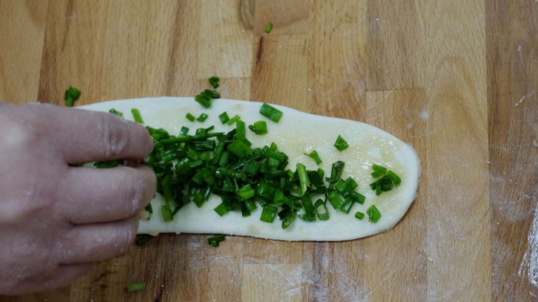 上海葱油饼,取一个小面团用擀面杖擀成椭圆形，然后涂上前面做好的油酥，再放上葱