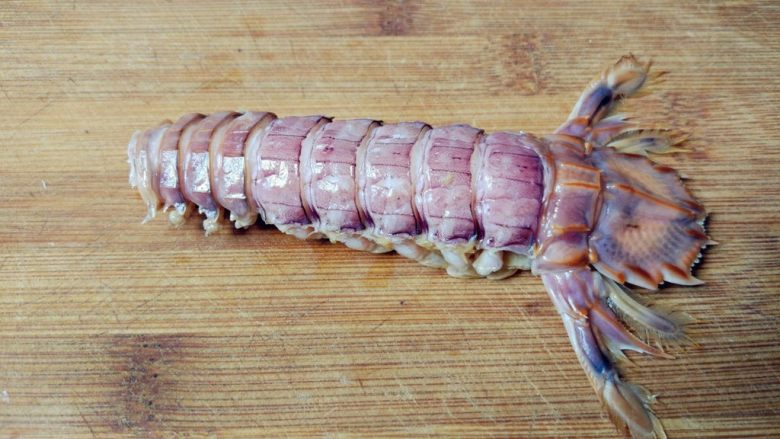 快速手剥皮皮虾,如图，掰掉剥好的背壳。这样可以直接吃肉了，如果想整条剥出，就继续往下。熟练的话，这个过程也就几秒足够了。