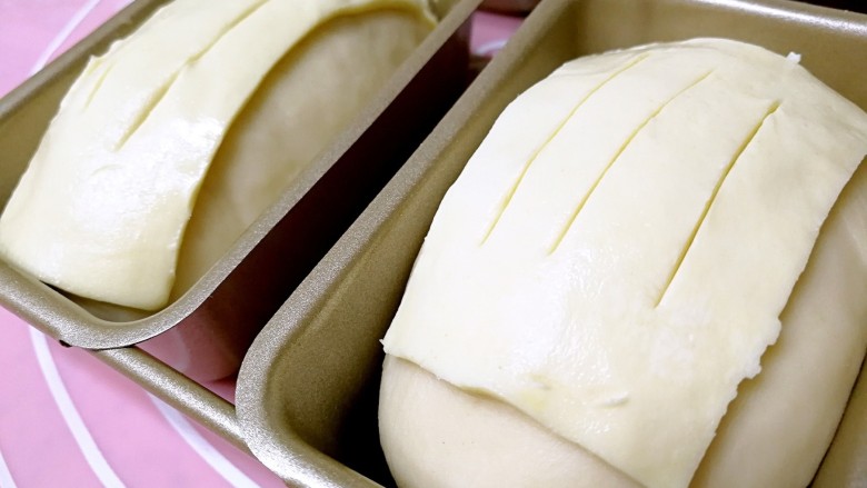 酥皮苹果小餐包,发至1倍大，把酥皮切成面包胚表面大小，盖在表面，用刀尖纵向切割几下。烤箱预热180度。