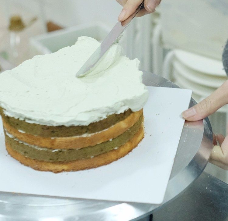 抹茶棋格蛋糕,转台上放一块原味在最外面的蛋糕胚，抹上一层薄薄的鲜奶油，然后再放一层抹茶在外面的蛋糕胚，一层隔一层的叠起来就可以啦