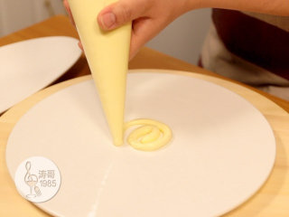 黄桃裙边蛋糕,先在一个平面圆盘中心挤一点瑞士奶油霜