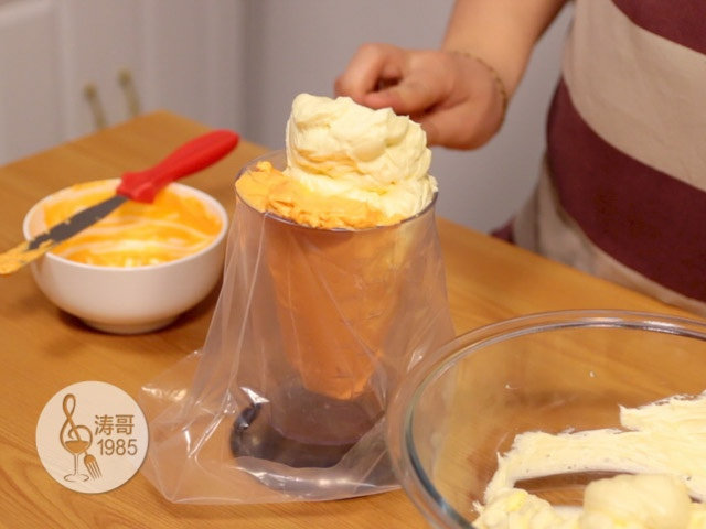 黄桃裙边蛋糕,橙色奶油霜装好后，用原色奶油霜来填满剩余的2/3