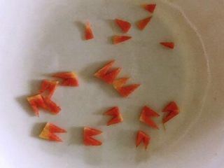小鸡玉米馒头，人见人爱，花见花开,胡萝卜用刀切成如图三角形形状，做鸡的嘴巴和脚丫子。